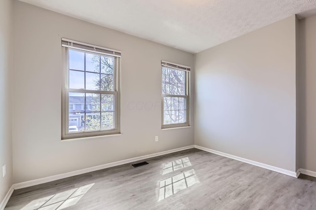 3225 Bellerive Dr, Pickerington, OH 43147 - empty room with visible vents, baseboards, a textured ceiling, and wood finished floors