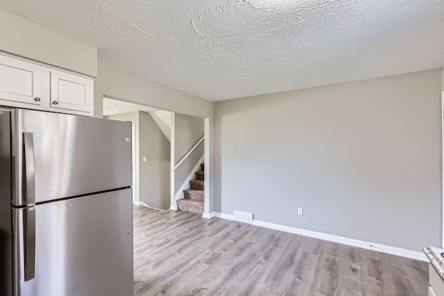 kitchen featuring white cabinetry, visible vents, light wood finished floors, and freestanding refrigerator