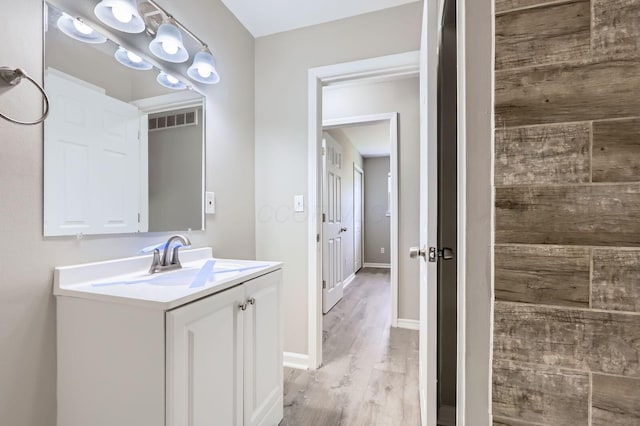 bathroom featuring visible vents, baseboards, wood finished floors, and vanity
