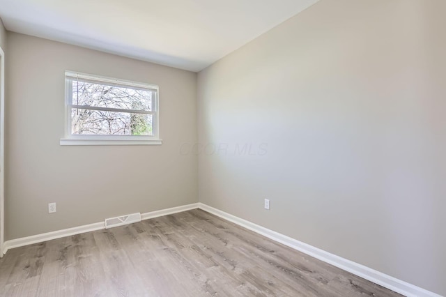 spare room with baseboards, wood finished floors, and visible vents