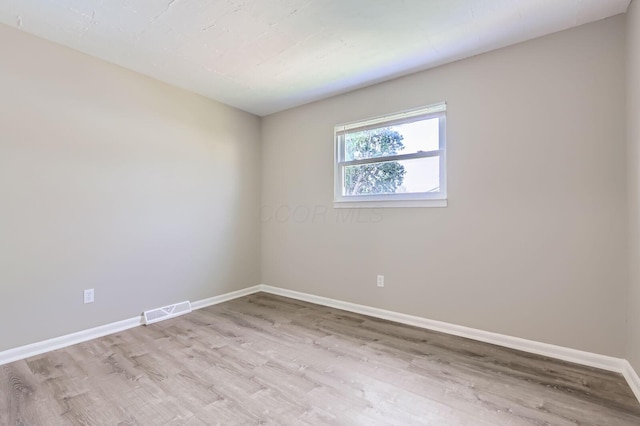 unfurnished room with visible vents, light wood finished floors, and baseboards