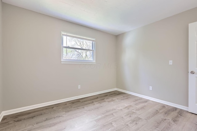 unfurnished room featuring baseboards and light wood finished floors