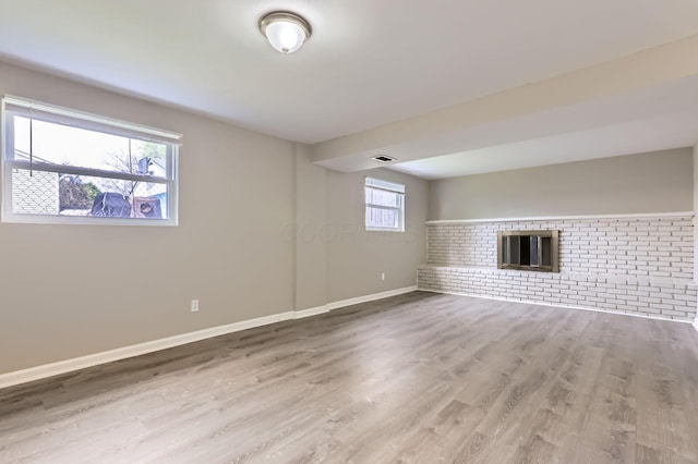 interior space featuring brick wall, baseboards, wood finished floors, and a fireplace