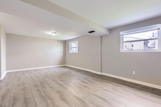 unfurnished room with light wood-type flooring, visible vents, and baseboards