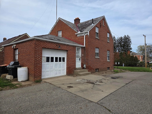 view of side of home with concrete driveway, brick siding, and a garage