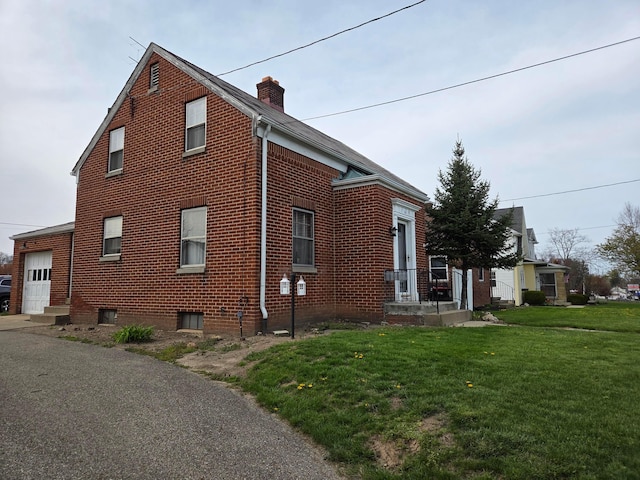 view of side of property with a lawn, a chimney, and a garage