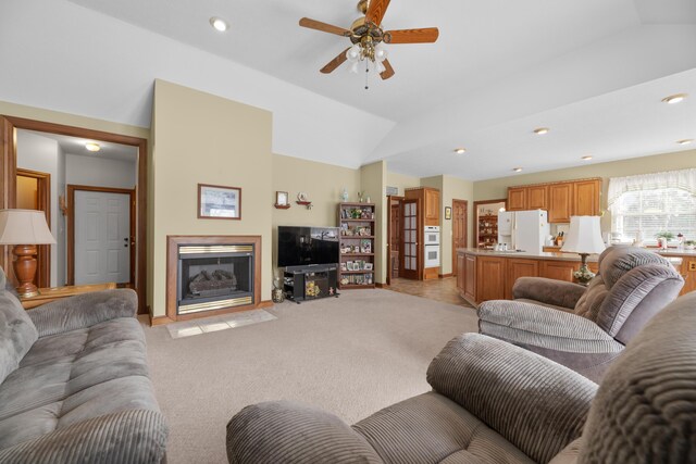 living room featuring a ceiling fan, recessed lighting, a fireplace with flush hearth, light colored carpet, and lofted ceiling