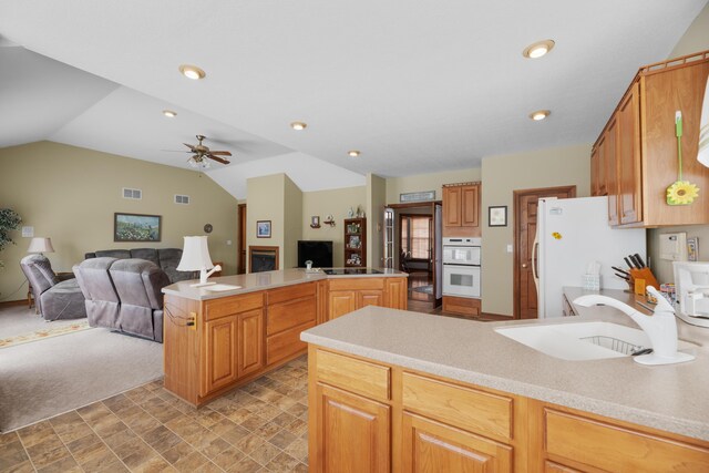 kitchen featuring open floor plan, white appliances, a sink, and a peninsula