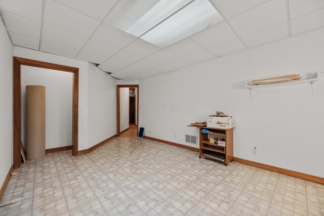 spare room with tile patterned floors, visible vents, a drop ceiling, and baseboards