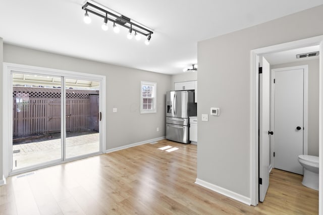 interior space featuring light wood-type flooring, baseboards, and visible vents