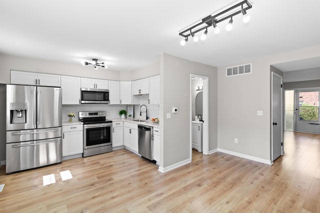 kitchen with visible vents, a sink, light countertops, appliances with stainless steel finishes, and decorative backsplash