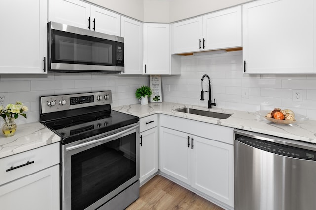 kitchen featuring a sink, white cabinets, appliances with stainless steel finishes, and light wood-style floors