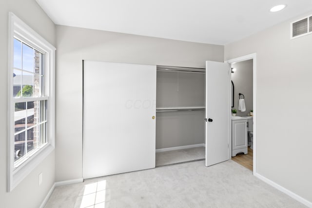 unfurnished bedroom with light carpet, visible vents, baseboards, and a closet