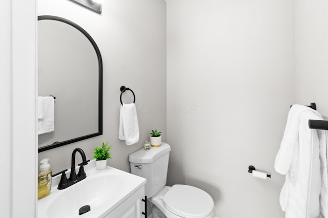 half bathroom featuring vanity and toilet