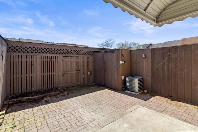 view of patio featuring a fenced backyard, central AC unit, and a gate