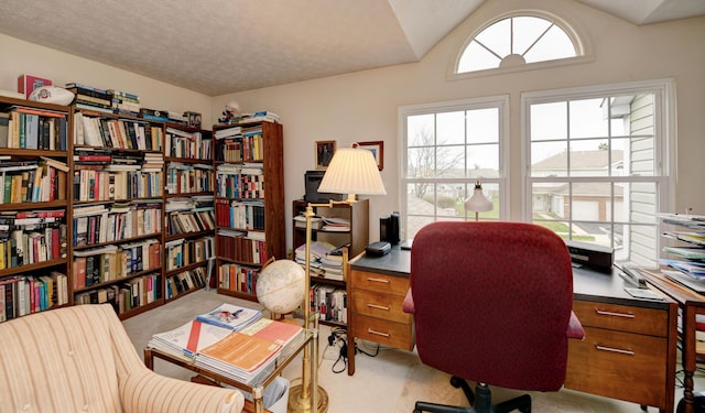 carpeted home office with vaulted ceiling