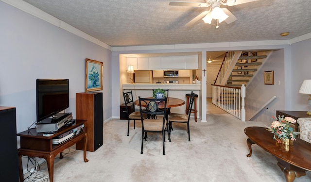 dining area with ceiling fan, a textured ceiling, light colored carpet, ornamental molding, and stairs
