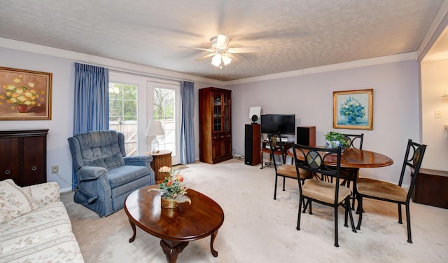 living area featuring light colored carpet, a ceiling fan, a textured ceiling, and ornamental molding