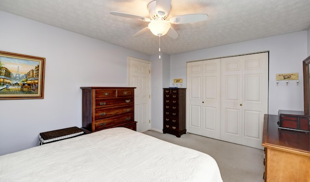 bedroom with a ceiling fan, light carpet, a closet, and a textured ceiling