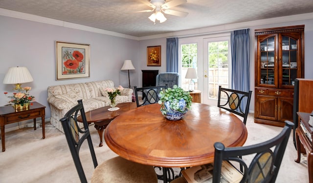 dining area featuring light colored carpet, a ceiling fan, and a textured ceiling