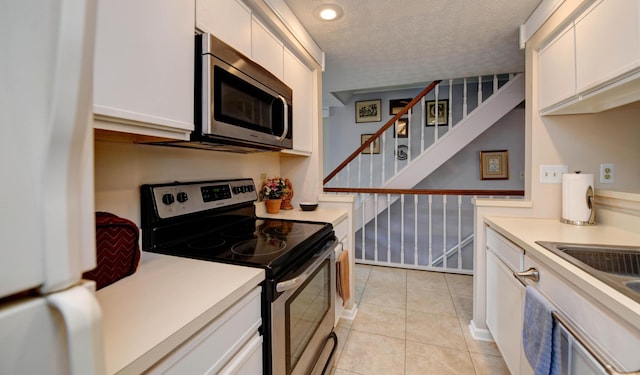 kitchen featuring appliances with stainless steel finishes, white cabinetry, light countertops, and a textured ceiling