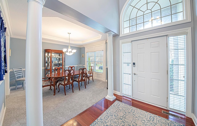 foyer entrance with visible vents, ornamental molding, decorative columns, a chandelier, and dark wood-type flooring