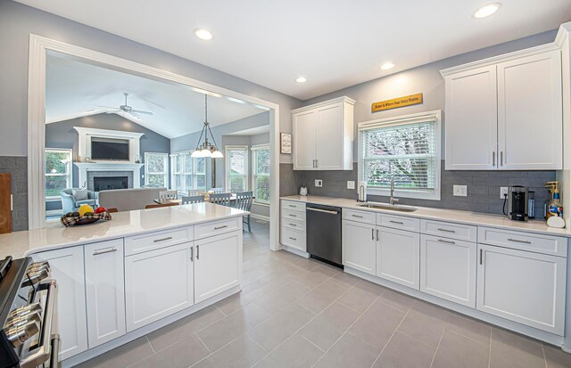 kitchen with a fireplace, a ceiling fan, dishwasher, light countertops, and stainless steel range oven