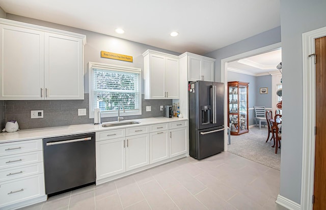 kitchen with dishwashing machine, white cabinets, black fridge, a sink, and light countertops