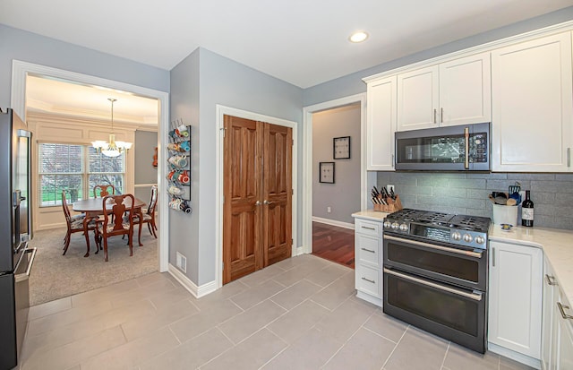 kitchen featuring white cabinetry, baseboards, appliances with stainless steel finishes, and an inviting chandelier