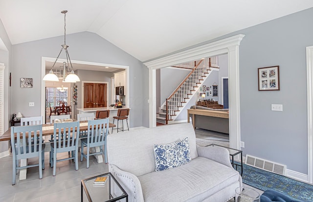 living area featuring baseboards, a chandelier, stairway, visible vents, and lofted ceiling