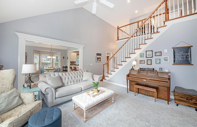 living room featuring high vaulted ceiling, ceiling fan, carpet, stairs, and baseboards