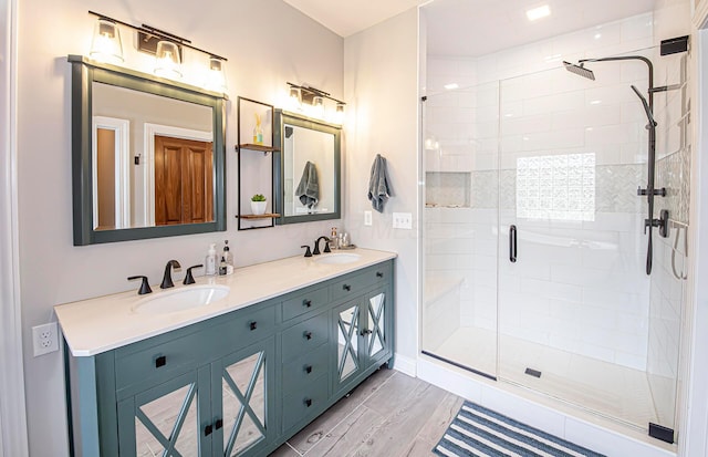 bathroom with a shower stall, double vanity, and a sink