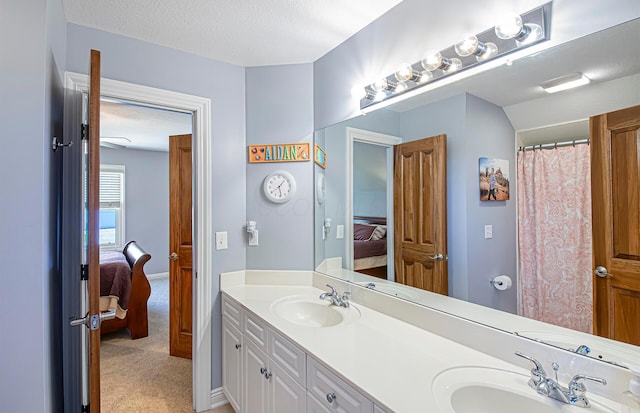 full bathroom with a textured ceiling, double vanity, a sink, and ensuite bath