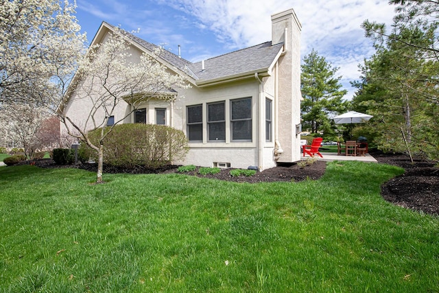 view of property exterior featuring a patio, roof with shingles, stucco siding, a chimney, and a yard