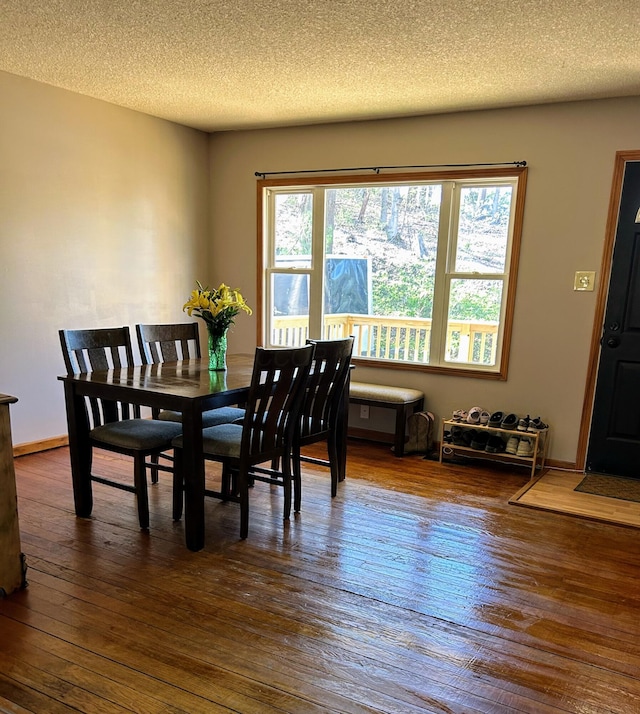 dining space with dark wood-type flooring and a textured ceiling