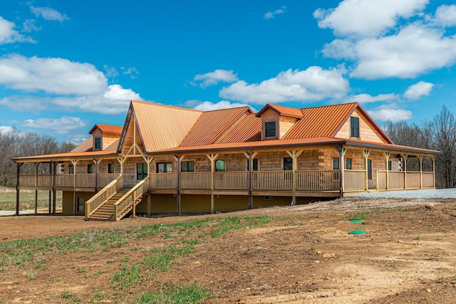 rear view of house with stone siding, metal roof, and stairs