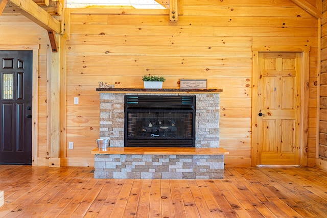 room details with wood walls, a stone fireplace, and wood finished floors