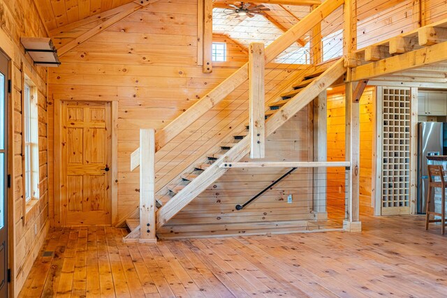 stairway with wooden walls, wood-type flooring, and vaulted ceiling