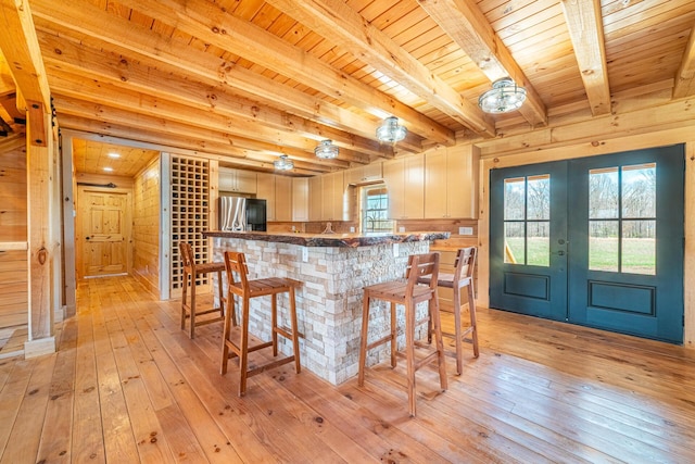 bar with stainless steel refrigerator with ice dispenser, french doors, light wood-type flooring, and wood ceiling