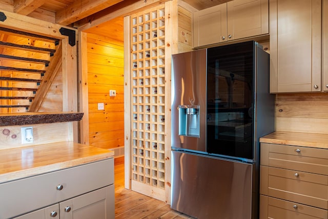 kitchen featuring wood counters, wooden walls, and stainless steel refrigerator with ice dispenser
