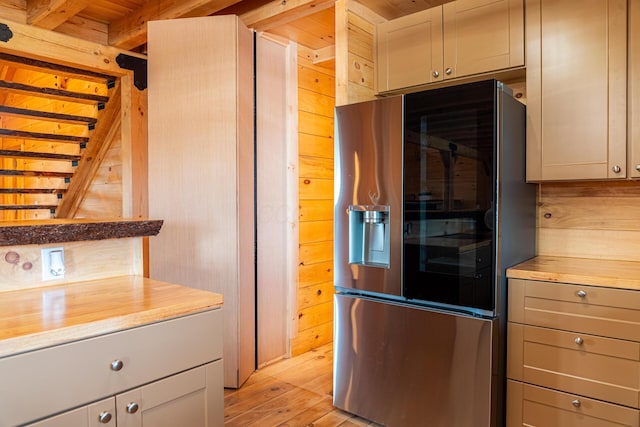 kitchen with wood walls, wood counters, light wood-style floors, and stainless steel fridge