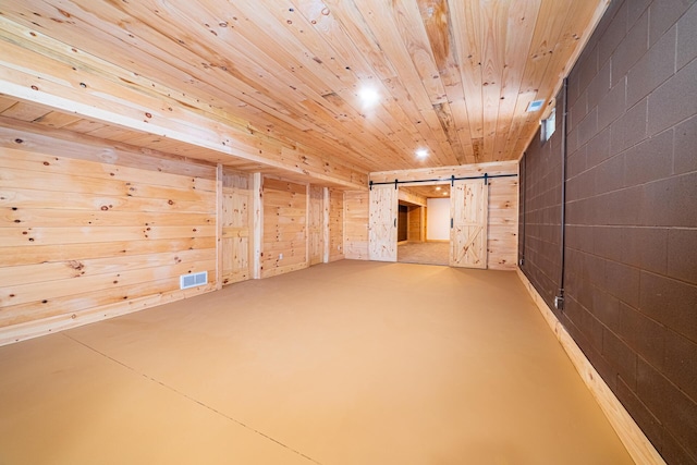 additional living space with visible vents, a barn door, wood ceiling, wooden walls, and concrete flooring