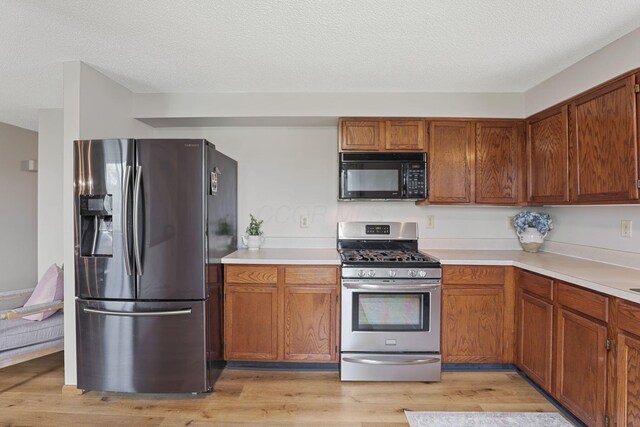 1581 Ringfield Dr, Galloway, OH 43119 - kitchen featuring light countertops, a textured ceiling, brown cabinetry, stainless steel appliances, and light wood finished floors
