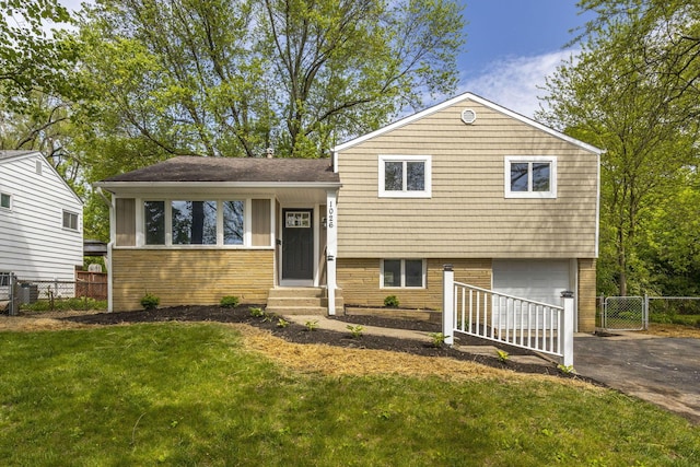 tri-level home featuring driveway, entry steps, an attached garage, a gate, and brick siding