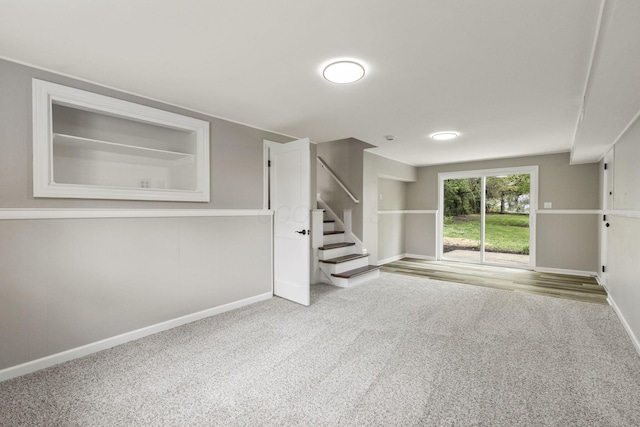 unfurnished living room with stairway, carpet flooring, and baseboards