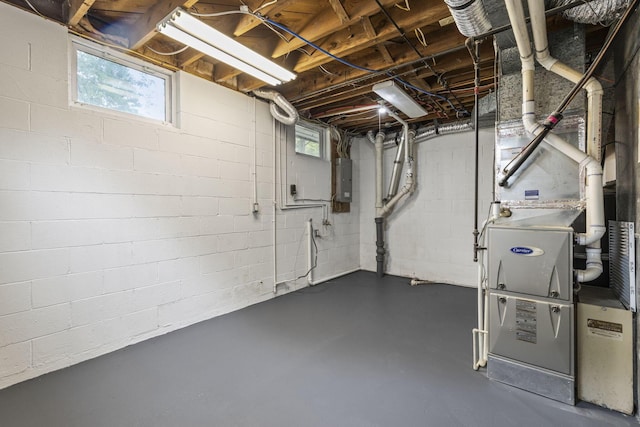 basement featuring electric panel, plenty of natural light, and concrete block wall