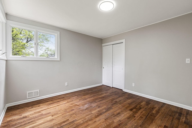 unfurnished bedroom with baseboards, wood finished floors, and a closet
