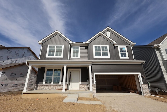 697 Clark Dr, Reynoldsburg, OH 43068 - view of front of house with covered porch, concrete driveway, a garage, stone siding, and board and batten siding