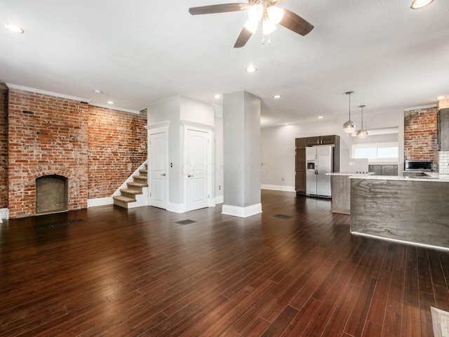 444 S 22nd St, Columbus, OH 43205 - unfurnished living room with a brick fireplace, ceiling fan, baseboards, stairs, and dark wood-style flooring