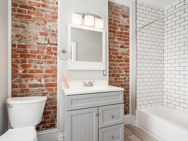 444 S 22nd St, Columbus, OH 43205 - full bathroom with toilet, vanity, brick wall, washtub / shower combination, and wood finished floors
